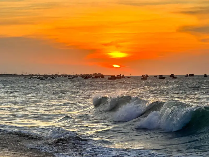 Pôr do sol com barcos de pesca na Praia do Farol RN